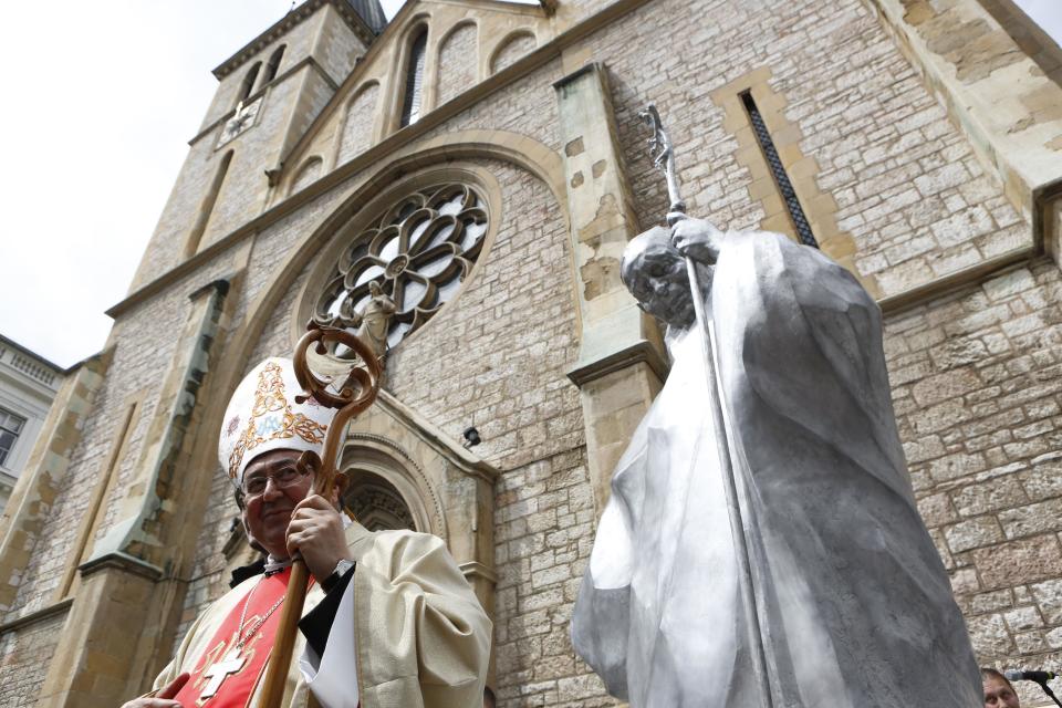 Bosnian Cardinal Vinko Puljic unveils the statue of Pope John Paul II in front of the cathedral in Sarajevo, Bosnia, on Wednesday, April 30, 2014. Thousands of Bosnians have celebrated the canonization of Pope John Paul II by unveiling a statue in the heart of Sarajevo. John Paul’s support for Sarajevo's resistance to nationalist efforts to destroy the traditional inter-cultural and inter-religious fabric of the city during the 1992-95 war made him very popular among the city's predominantly Muslim population. The crowd shouted “long live the pope” as the three meter-high statue was unveiled Wednesday in front of the cathedral. (AP Photo/Amel Emric)