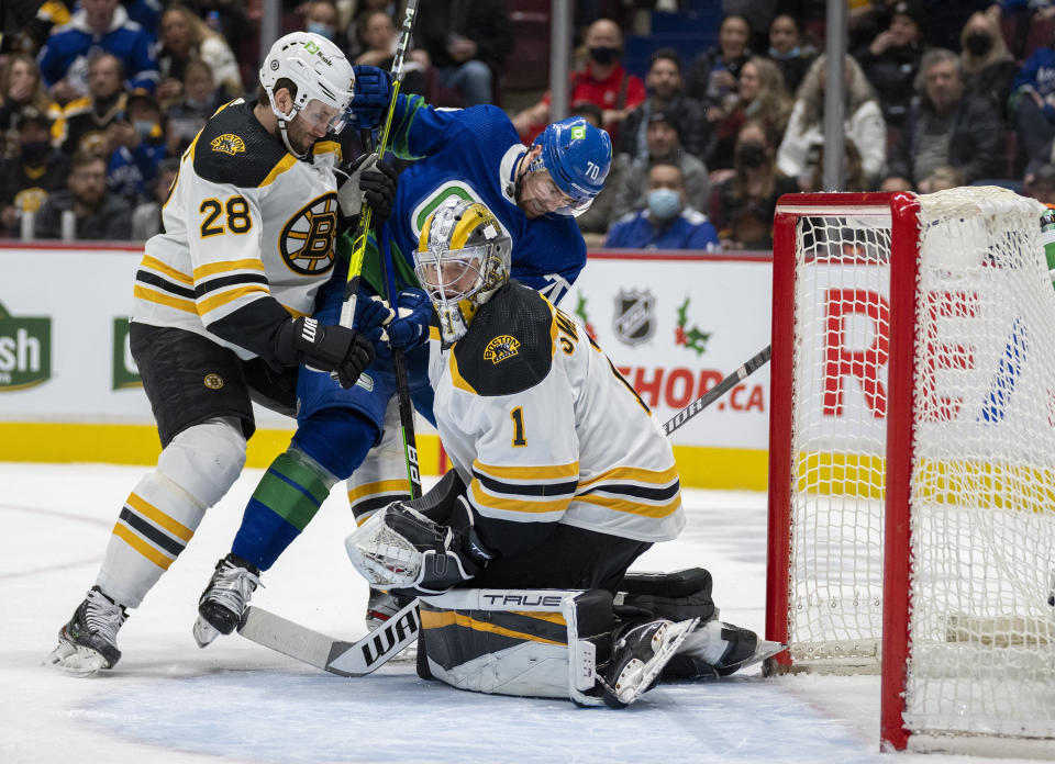 Boston Bruins defenseman Derek Forbort (28) tries to clear Vancouver Canucks left wing Tanner Pearson (70) from in front of Boston Bruins goaltender Jeremy Swayman (1) during the second period of an NHL hockey game Wednesday, Dec. 8, 2021 in Vancouver, British, Columbia. (Jonathan Hayward/The Canadian Press via AP)