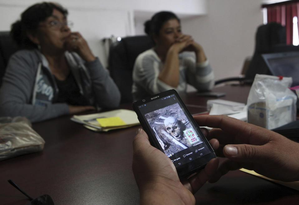 Pablo Reyes holds a cell phone showing a photo of an unidentified skull that was discovered in the Arizona desert, at the Human Right State Commission office where he, his mother Cesaria Orona, left, and Maria Elena Luna, unrelated, share details of the disappearances of their family members Armando Reyes and Juan Lorenzo Luna, who are brother-in-laws, with the Argentine Forensic Anthropologist Team in Chihuahua, Mexico, March 22, 2018. Armando Reyes and Juan Lorenzo Luna went missing together in the Arizona desert as they tried to make it to the U.S. (AP Photo/Marco Ugarte)