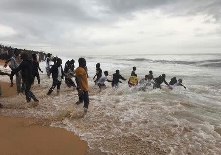People rush to pull the wreckage of a propeller-engine cargo plane is seen after it crashed in the sea near the international airport in Ivory Coast's main city, Abidjan, October 14, 2017. REUTERS/Ange Aboa