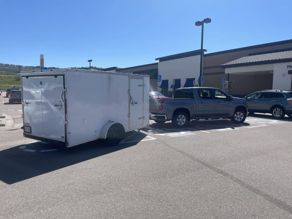 A truck with a trailer taking up multiple handicapped spots