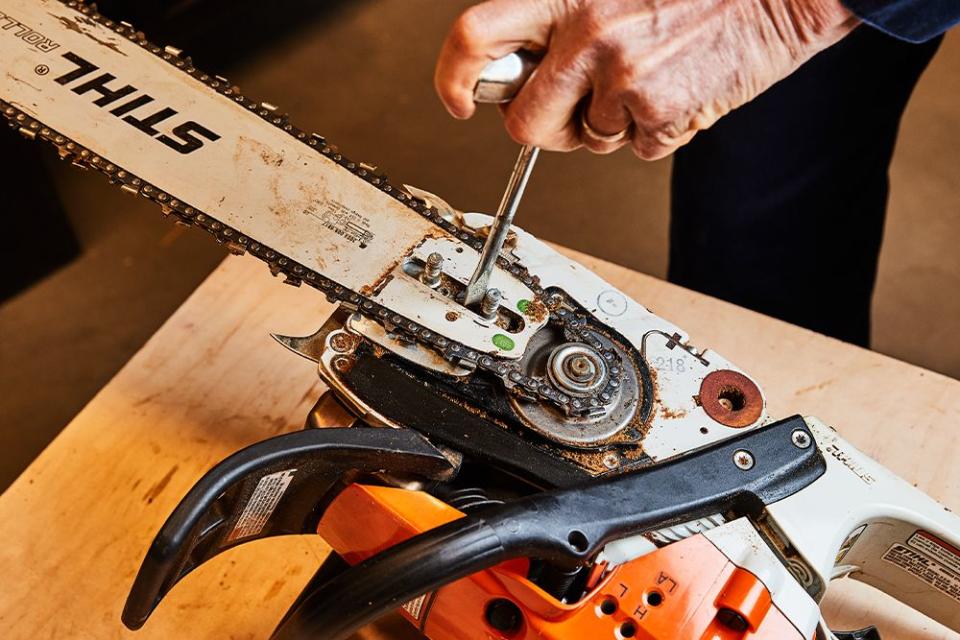 a person tightening up a chainsaw chain