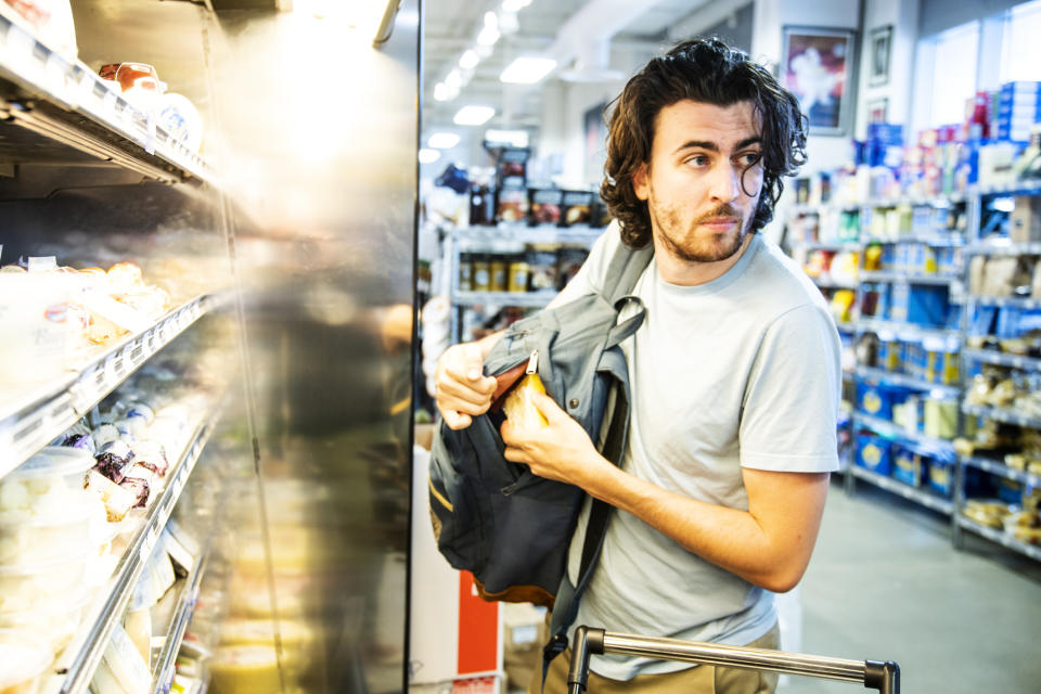 A man opening his backpack in a grocery store