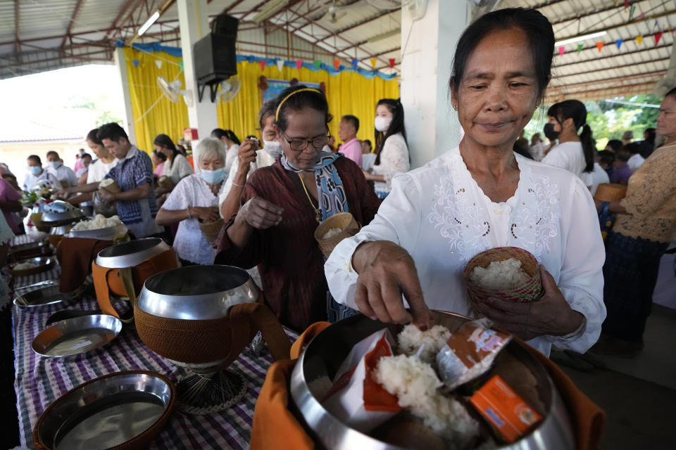 Relatives of the victims offer food into monk bowls during the Buddhist ceremony in the rural town of Uthai Sawan, in Nong Bua Lamphu province, northeastern Thailand, Friday, Oct. 6, 2023. A memorial service takes place to remember those who were killed in a grisly gun and knife attack at a childcare center. A former police officer killed 36 children and teachers in the deadliest rampage in Thailand's history one year ago. (AP Photo/Sakchai Lalit)
