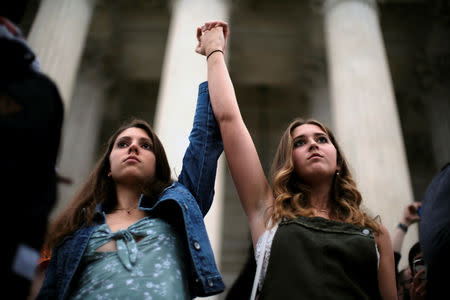 Annabella Helman of Indianapolis, Indiana, and Olivia McAuliffe of McLean, Virginia join hands as protesters overrun the steps of the U.S. Supreme Court as Brett Kavanaugh is sworn in as an Associate Justice in Washington, U.S., October 6, 2018. REUTERS/James Lawler Duggan