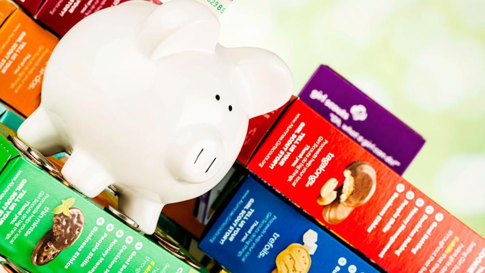 "Suffolk, Virginia, USA - March 10, 2013: A horizontal format studio shot of several boxes of different flavored Girl Scout Cookies, with a piggy bank and money sitting on the top to convey the concept of fundraising by selling the cookies.