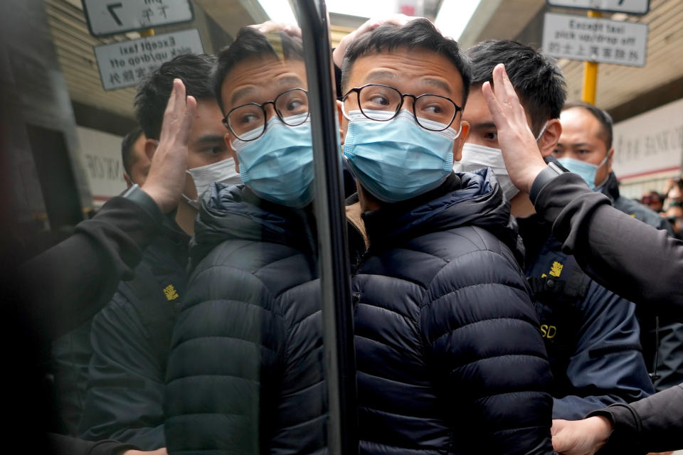 Editor of Stand News Patrick Lam, center, is escorted by police officers into a van after they searched evidence at his office in Hong Kong, Wednesday, Dec. 29, 2021. Hong Kong police raided the office of the online news outlet on Wednesday after arresting several people for conspiracy to publish a seditious publication. (AP Photo/Vincent Yu)