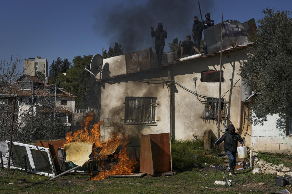 Palestinian men stand on the roof of a house as Israeli police prepare to evict a family, in the flashpoint east Jerusalem neighborhood of Sheikh Jarrah, Monday, Jan. 17, 2022. Palestinian residents of Sheikh Jarrah held a tense standoff with Israeli authorities as police came to evict them from the disputed property. Several residents climbed onto the roof with gas tanks and threatened to set them on fire if the Jerusalem municipality followed through with the eviction. (AP Photo/Mahmoud Illean)