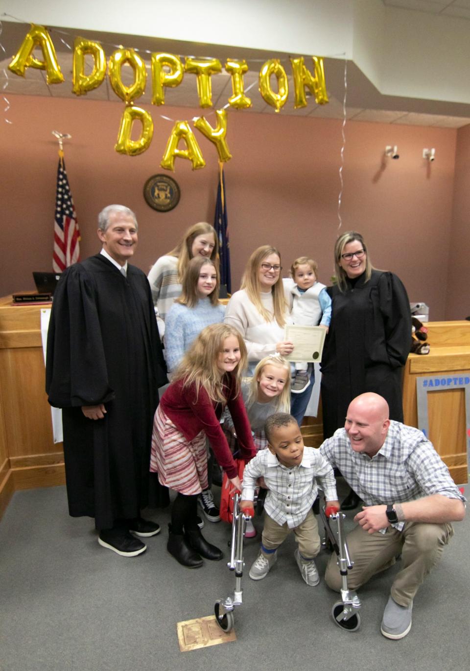 Michigan Supreme Court Justice Brian Zahra, left, and Livingston County Probate Judge Miriam Cavanaugh, right, join the Setty family after they adopt one more to their growing family Tuesday, Nov. 23, 2021.