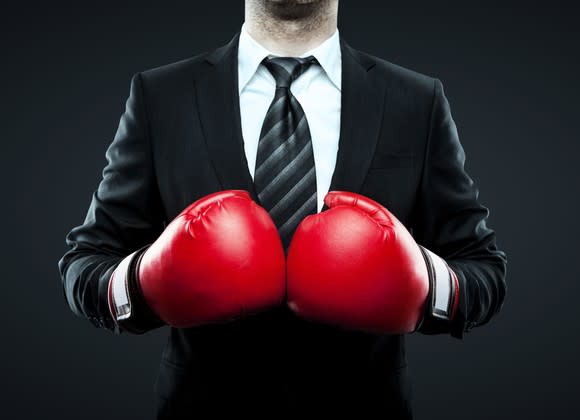 A businessman in a suit wearing boxing gloves.