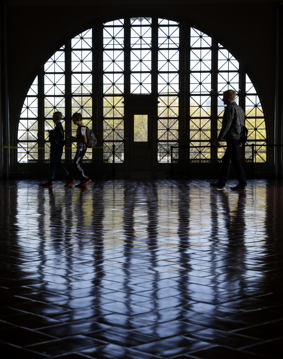 Visitors walk around the registry room on Ellis Island in New York, Monday, Oct. 28, 2013. The island that ushered millions of immigrants into the United States received visitors Monday for the first time since Superstorm Sandy. Sandy swamped boilers and electrical systems and left the 27.5-acre island without power for months. (AP Photo/Seth Wenig)