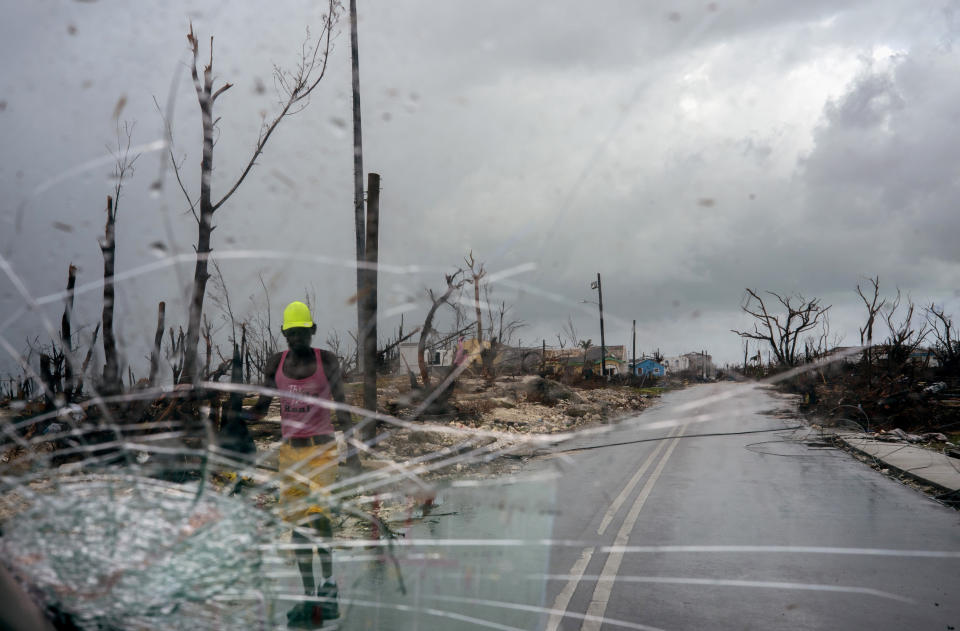 Trees destroyed by Hurricane Dorian line a road as a man walks by, in Abaco, Bahamas, Monday, Sept. 16, 2019. Dorian hit the northern Bahamas on Sept. 1, with sustained winds of 185 mph (295 kph), unleashing flooding that reached up to 25 feet (8 meters) in some areas. (AP Photo/Ramon Espinosa)