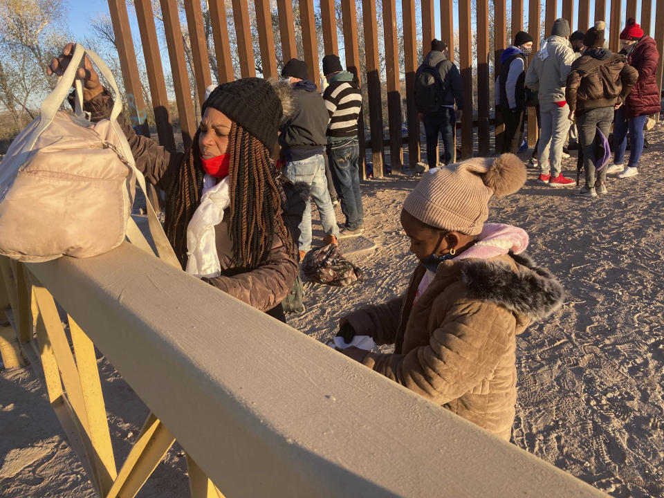 FILE - A Cuban woman and her daughter wait in line to be escorted to a Border Patrol van for processing in Yuma, Ariz., Sunday, Feb. 6, 2022, hoping to remain in the United States to seek asylum. A federal appeals court has upheld sweeping asylum restrictions to prevent spread of COVID-19 but restored protections to prevent migrant families from being expelled to their home countries without a chance to plead their cases. (AP Photo/Elliot Spagat, File)