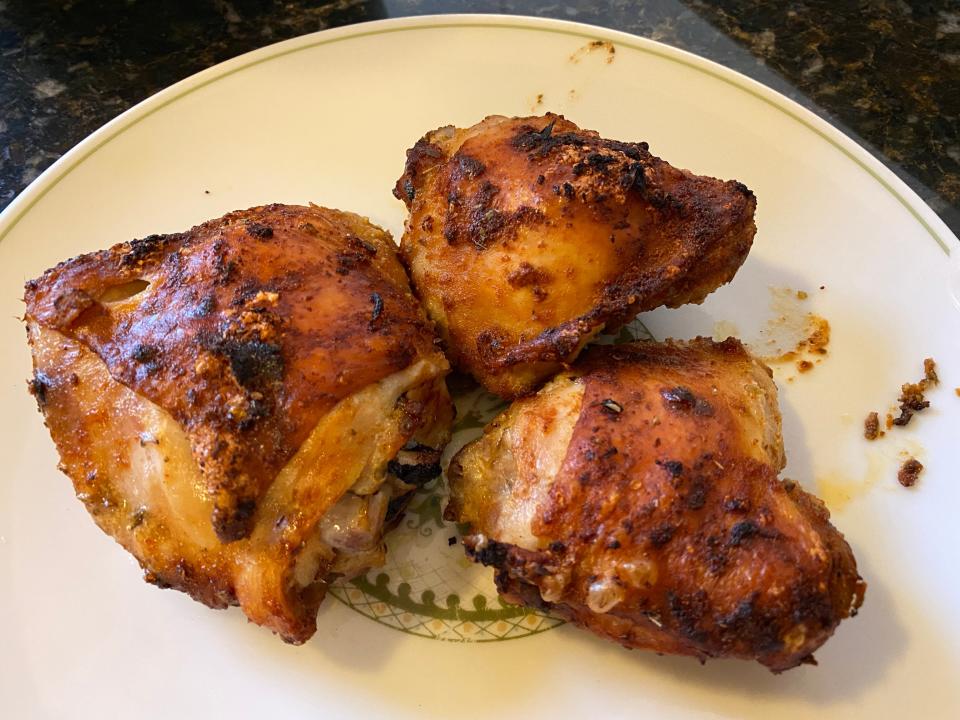 three pieces of air fried Chicken thighs on a white plate