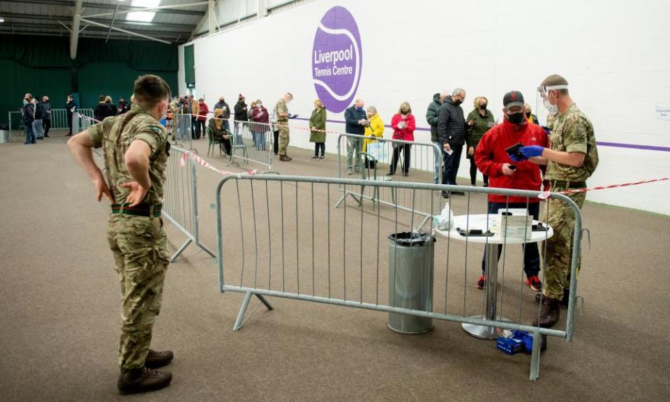 Two uniformed British soldiers deal with a queue of people awaiting Covid-19 testing in Liverpool as part of Operation Moonshot.