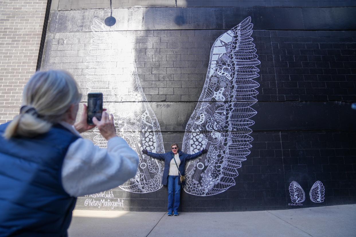 Amy Peverall from Winston-Salem, North Carolina, poses for a picture in front of the "What Lifts You" mural in the Gulch.