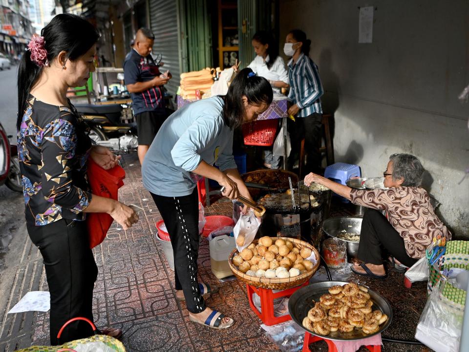 A customer buys pastries from a street vendor in Phnom Penh.