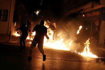 A masked demonstrator (C) is engulfed in flames as clashes with riot police take place during a rally marking four years since the fatal stabbing of Greek anti-fascism rapper Pavlos Fyssas by a supporter of the ultranationalist Golden Dawn party in Athens, Greece, September 16, 2017. REUTERS/Alkis Konstantinidis