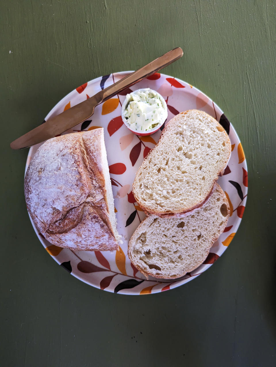 This photo shows a fresh-baked crusty country loaf with a pot of herbed compound butter. Handcrafted, artisanal breads are more popular than ever. Food & Wine’s Chandra Ram suggests making an easy condiment to accompany your breads by mixing spices or herbs into regular butter and chilling before serving. (Kim Cook via AP)