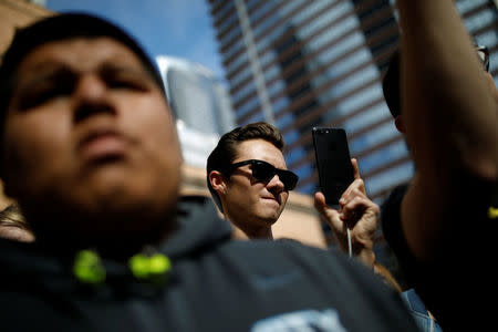 David Hogg, a student and shooting survivor from Marjory Stoneman Douglas High School uses his cellphone as Manuel Oliver, the father of Joaquin Oliver one of the victims of the mass shooting, paints a mural to commemorate the victims and promote gun control in Los Angeles, California, U.S., April 7, 2018. REUTERS/Carlos Garcia Rawlins