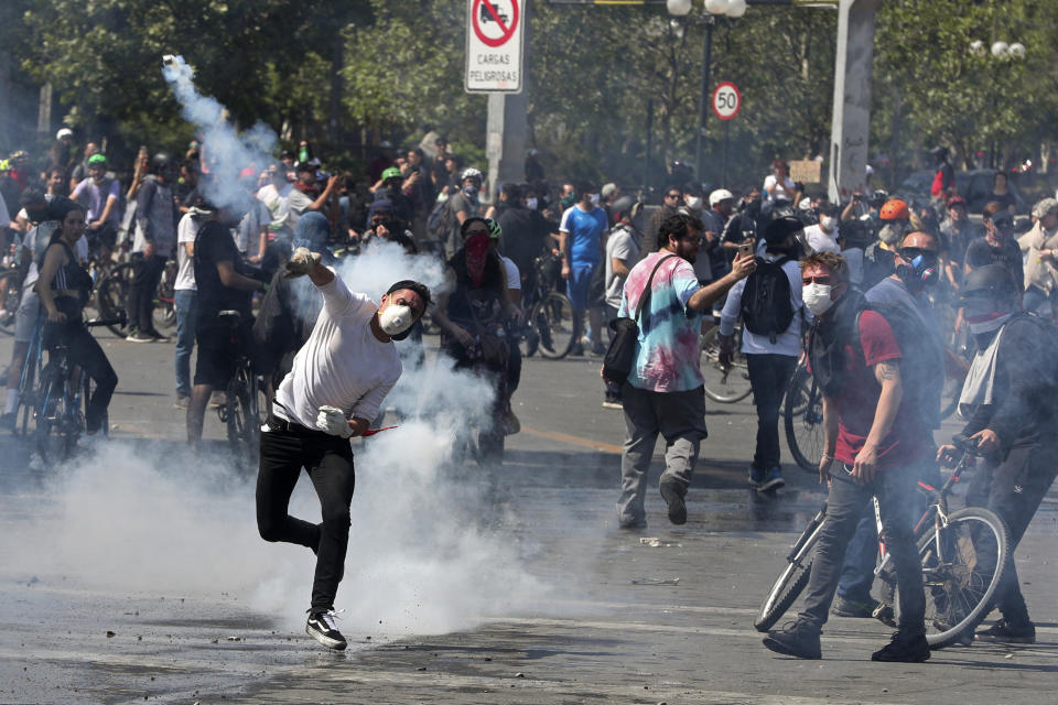 A protester returns a tear gas canister to police during clashes in Santiago, Chile, Sunday, Oct. 20, 2019. Protests in the country have spilled over into a new day, even after President Sebastian Pinera cancelled the subway fare hike that prompted massive and violent demonstrations. (Photo: Esteban Felix/AP)