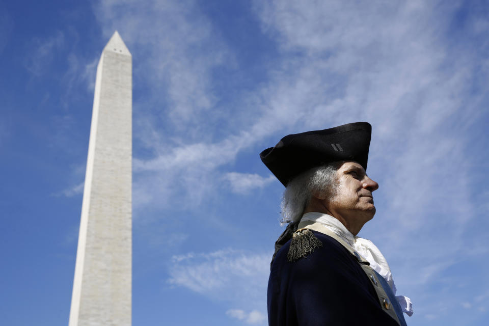 FILE - John Lopes, playing the part of President George Washington, stands near the Washington Monument following a ribbon-cutting ceremony with first lady Melania Trump to re-open the monument, Thursday, Sept. 19, 2019, in Washington. Like the other Founding Fathers, George Washington was uneasy about the idea of publicly celebrating his life. He was the first leader of a new republic — not a tyrant. (AP Photo/Patrick Semansky, File)