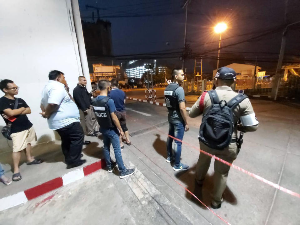 Police and bystanders stand near the scene of a shooting at the Terminal 21 mall, in Korat, Thailand, Saturday, Feb. 8, 2020. Police in northeastern Thailand said a soldier shot multiple people on Saturday, killing more than 10, and was holed up at a popular shopping mall. (AP Photo)