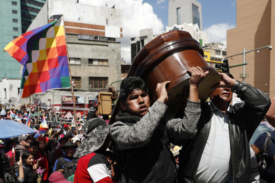 Men carry the coffin that contain the remains of a person killed in clashes between supporters of former President Evo Morales and security forces, in La Paz, Bolivia, Thursday, Nov. 21, 2019. Mourners and anti-government demonstrators marched to La Paz with the coffins of some of the at least eight people killed Tuesday when security forces cleared a blockade of a fuel plant by Morales' backers in the city of El Alto. (AP Photo/Juan Karita)