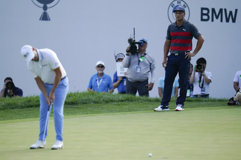 Bryson DeChambeau, right, watches as Patrick Cantlay putts on the 16th green during the final round of the BMW Championship golf tournament, Sunday, Aug. 29, 2021, at Caves Valley Golf Club in Owings Mills, Md. (AP Photo/Julio Cortez)
