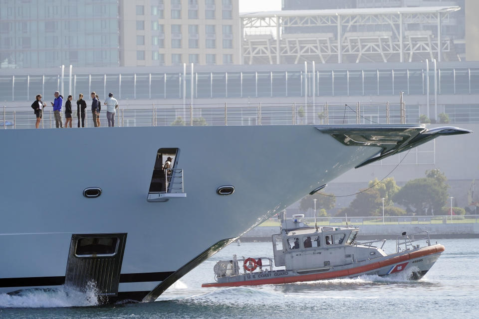 People stand on the deck of the super yacht Amadea as it is escorted by a Coast Guard vessel in the San Diego Bay Monday, June 27, 2022, seen from Coronado, Calif. The $325 million superyacht seized by the United States from a sanctioned Russian oligarch arrived in San Diego Bay on Monday. (AP Photo/Gregory Bull)