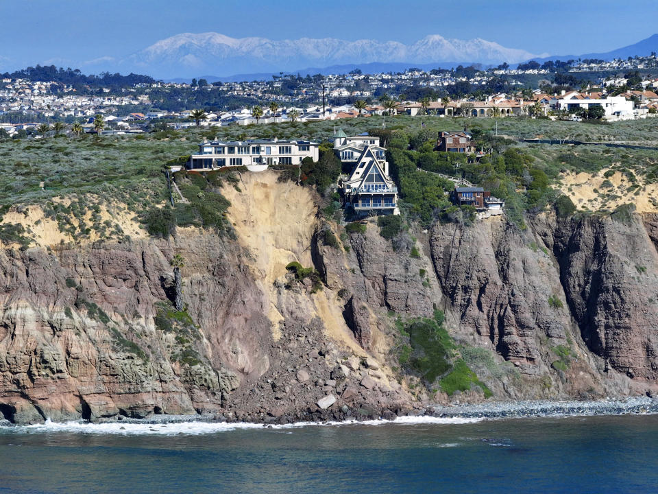 Cliff-top houses along Scenic Drive sit close to a landslide in Dana Point, Calif., on Tuesday, Feb. 13, 2024. The three homes affected by the recent deluge of rain across Orange County are being monitored but don't appear to be in imminent danger, county officials said. (Jeff Gritchen/Orange County Register, SCNG via AP)