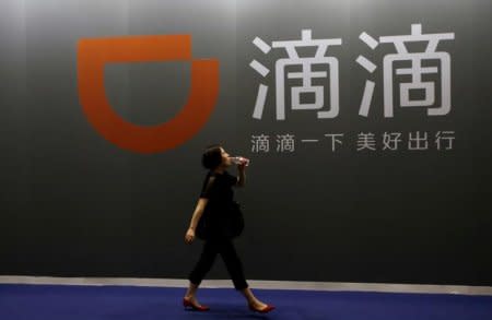 FILE PHOTO - A woman walks past Didi Chuxing's booth at the Global Mobile Internet Conference (GMIC) 2017 in Beijing, China April 28, 2017. REUTERS/Jason Lee