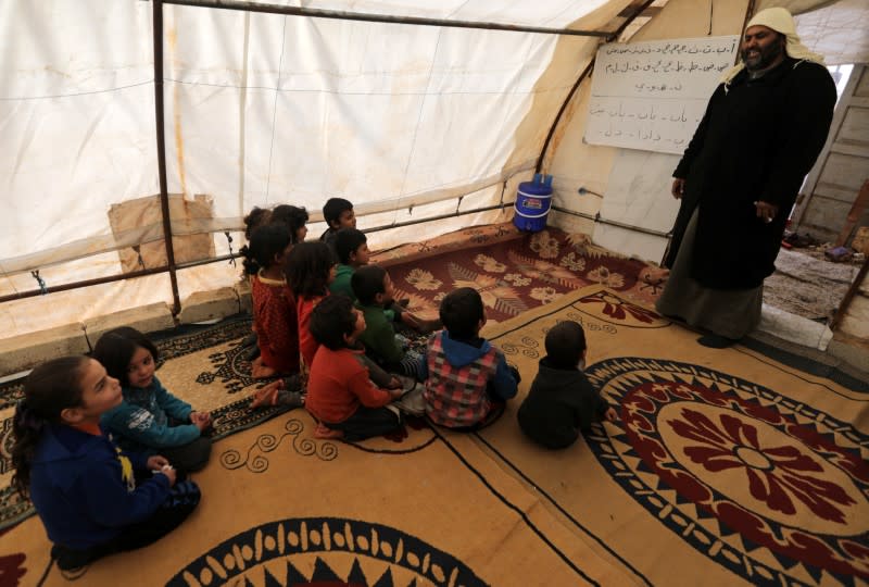Students sit together at a makeshift school in a tent in Azaz