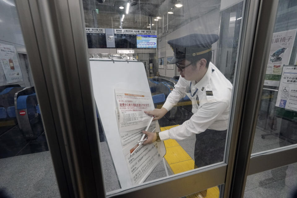 A staff member adjusts update notice paper on suspending operations of the Shinkansen or bullet train on Oct. 12-13 due to Typhoon Hagibis, at Tokyo Station in Tokyo Saturday, Oct. 12, 2019. Tokyo and surrounding areas braced for a powerful typhoon forecast as the worst in six decades, with streets and trains stations unusually quiet Saturday as rain poured over the city. (AP Photo/Eugene Hoshiko)