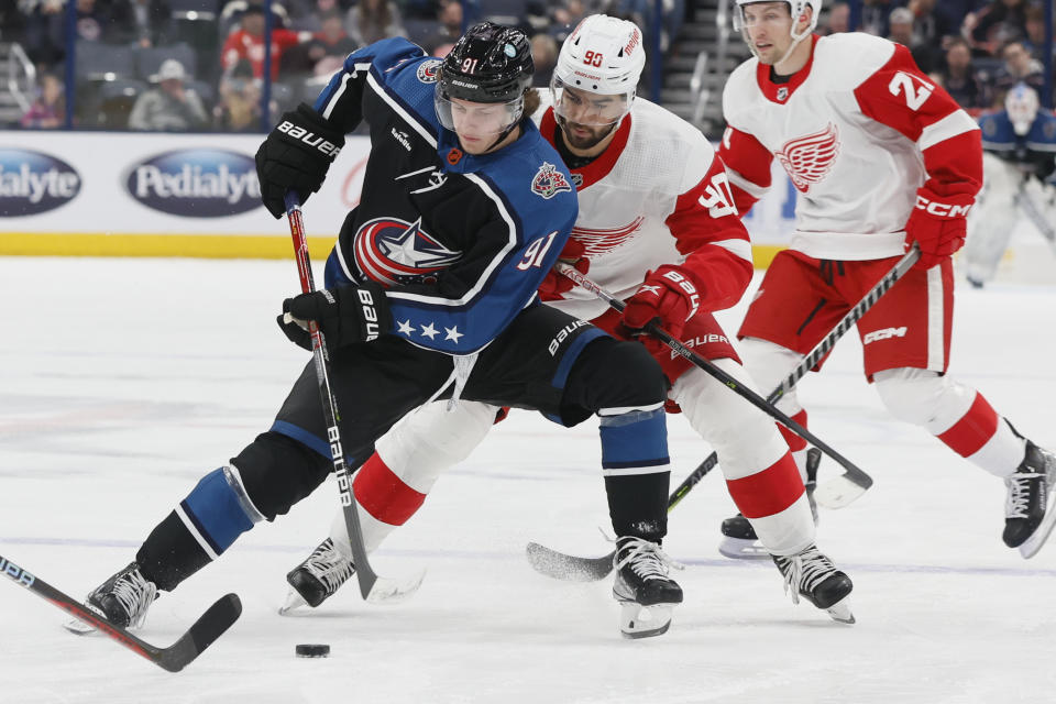 Columbus Blue Jackets' Kent Johnson, left, keeps the puck away from Detroit Red Wings' Joe Veleno during the second period of an NHL hockey game on Sunday, Dec. 4, 2022, in Columbus, Ohio. (AP Photo/Jay LaPrete)