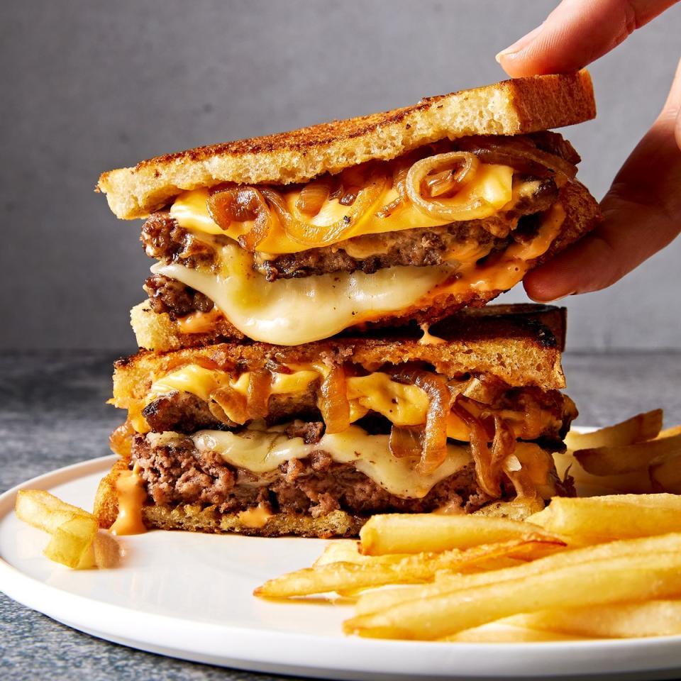 a person holding a large burger