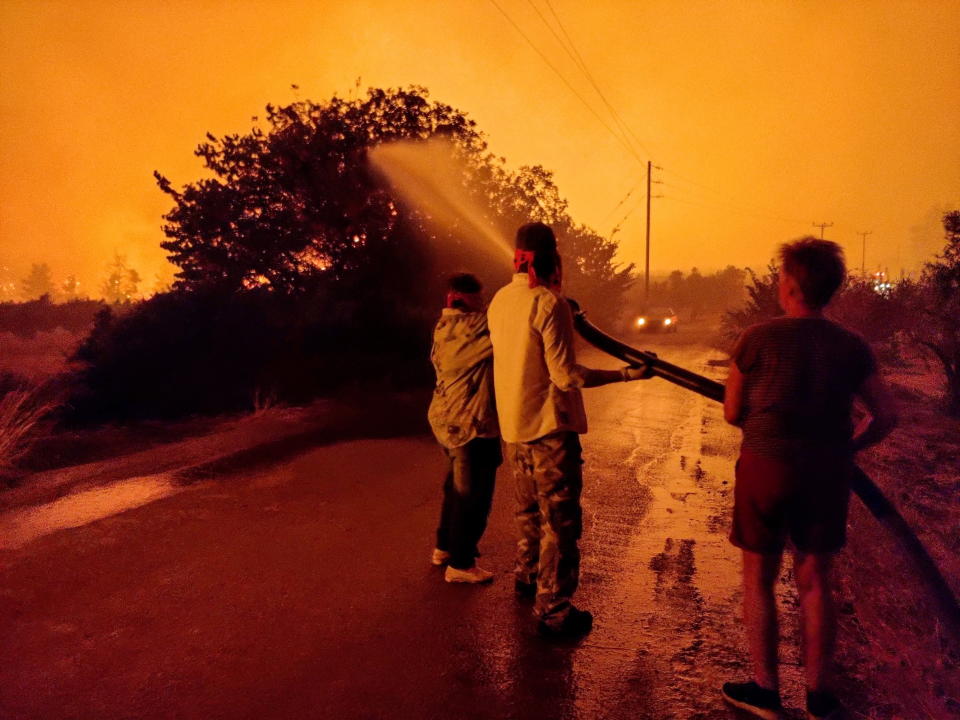 Residents hold a hose aimed at a wildfire on Evia island. Source: EPA