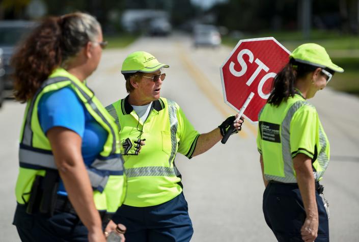 Whistle in hand, Port St. Lucie Police School Crossing Guard Teresa Gasparre (center) stands in the middle of Southeast Floresta Drive to keeps her mock students safe crossing the roadway during the crossing guard's annual Traffic Certification Training on Friday, Aug. 5, 2022, across from Floresta Elementry School in Port St. Lucie. &quot;It protects our kids,&quot; Gasparre said. &quot;because I enjoy kids, and working, and I want the kids to be safe.&quot;