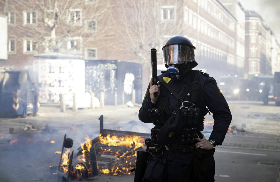 FILE - Danish police officers stand guard next to a fire lit by people who protested after a far-right provocateur tossed a copy of the Quran in the air in an immigrant neighborhood in Copenhagen, Sunday, April 14, 2019. Denmark's government on Friday, Aug. 25, 2023. said it would present a law proposal that would make it illegal to desecrate the Quran or other religious holy books in the Scandinavian country that has a recent string of public desecrations by a handful of anti-Islam activists — protests that have sparked angry demonstrations in Muslim countries. (Philip Davali/Ritzau Scanpix via AP, File)