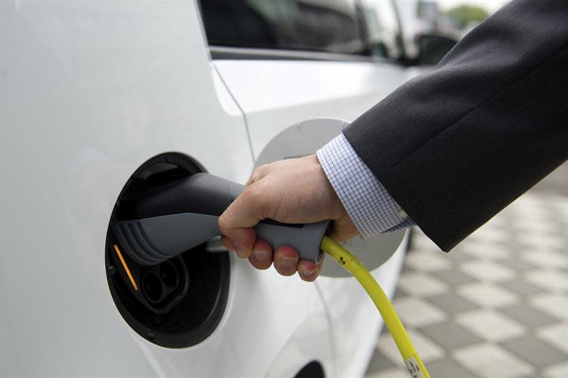 Foto: Un hombre conecta el cargador a un coche eléctrico. EFE/Archivo