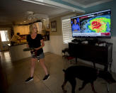 Kristie Fisher, center, catches the latest on Hurricane Dorian on television at the home of her boyfriend Joey Spalding, back left, as they finish packing all of their belongings into a rental truck, Tuesday, Sept. 3, 2019, in Tybee Island, Ga. Last year Spalding's home was flooded when Hurricane Irma pushed three feet of storm surge into his home. (AP Photo/Stephen B. Morton)