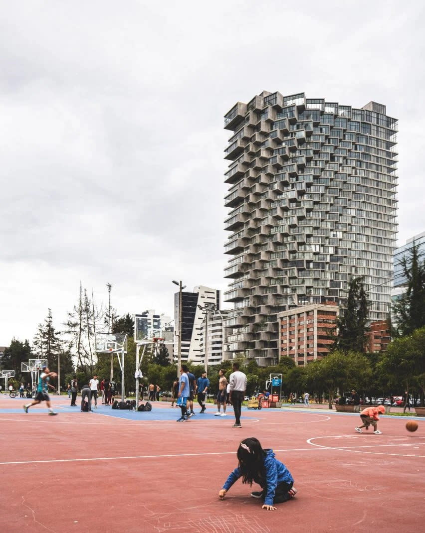 Adults shoot hoops and kids play with chalk at the IQON building basketball court. 