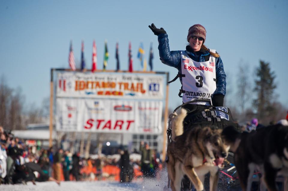 Musher Paige Drobny, of Fairbanks, waves to the crowd after she leaves the staring line of the Iditarod Trail Sled Dog Race on Willow Lake, Sunday, March 2, 2014, in Willow, Alaska. The race will take mushers nearly a thousand miles to the finish line in Nome, on Alaska's western coast. (AP Photo/Anchorage Daily News, Marc Lester)