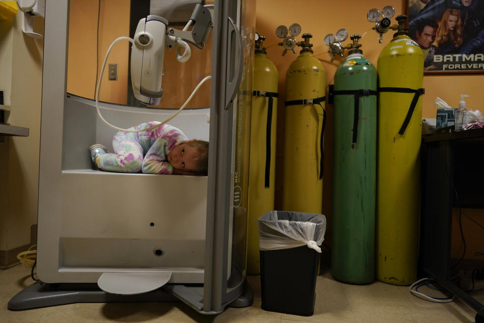 Lexie Stroiney, de 6 años, se acurruca en una cámara de pletismografía durante su prueba de función pulmonar el 26 de enero de 2022, en el Children's National Hospital en Washington, D.C. Lexie tenía COVID-19 y participó en un estudio de varios años financiado por los NIH para observar el impacto del COVID-19 en la salud y la calidad de vida de los niños. (AP Foto/Carolyn Kaster)