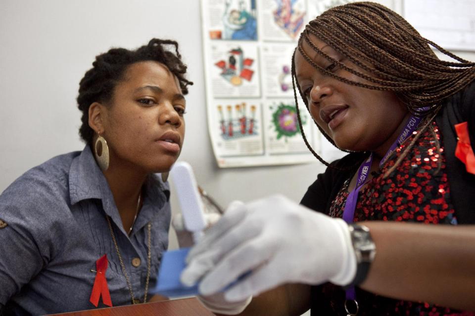 In this photo taken June 27, 2012, Natrussa Williams, an HIV tester and counselor, right, explains how the results of the oral HIV test will show up to Katherine Tapp, 26, of New York City, inside the HIV Testing Room at the Penn Branch of the District of Columbia Department of Motor Vehicles, in southeast Washington. An AIDS-free generation: It seems an audacious goal, considering how the HIV epidemic still is raging around the world. Yet more than 20,000 international HIV researchers and activists will gather in the nation's capital later this month with a sense of optimism not seen in many years _ hope that it finally may be possible to stem the spread of the AIDS virus. (AP Photo/Jacquelyn Martin)