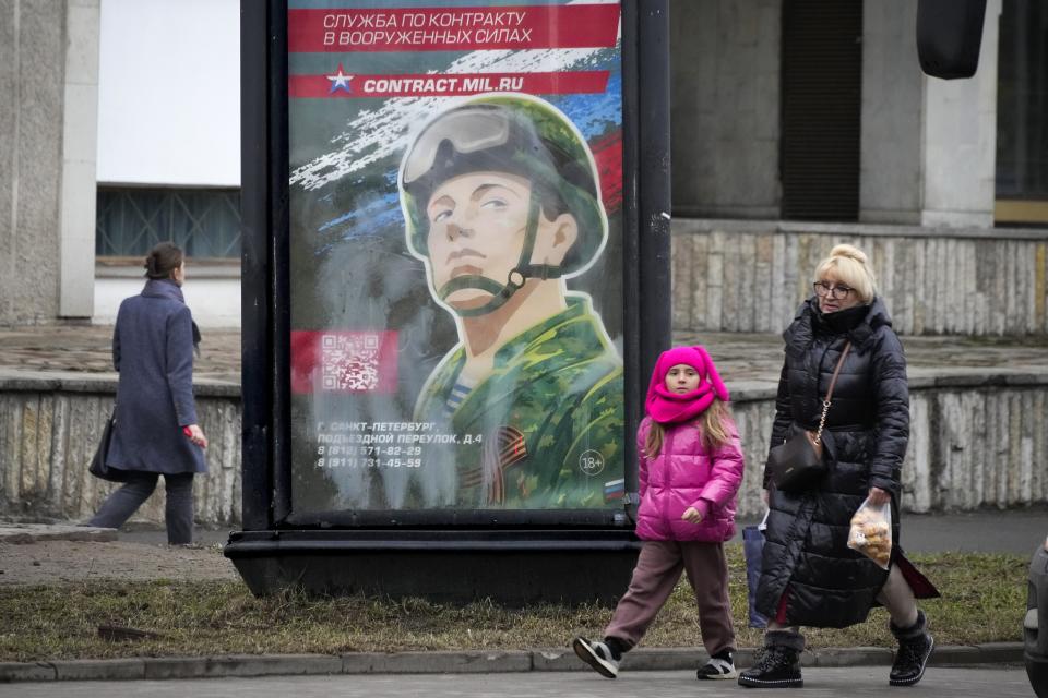 People walk past an army recruiting billboard with the words "Military service under contract in the armed forces" in St. Petersburg, Russia, Friday, March 24, 2023. A campaign to replenish Russian troops in Ukraine with more soldiers appears to be underway again, with makeshift recruitment centers popping up in cities and towns, and state institutions posting ads promising cash bonuses and benefits to entice men to sign contracts enabling them to be sent into the battlefield. (AP Photo)