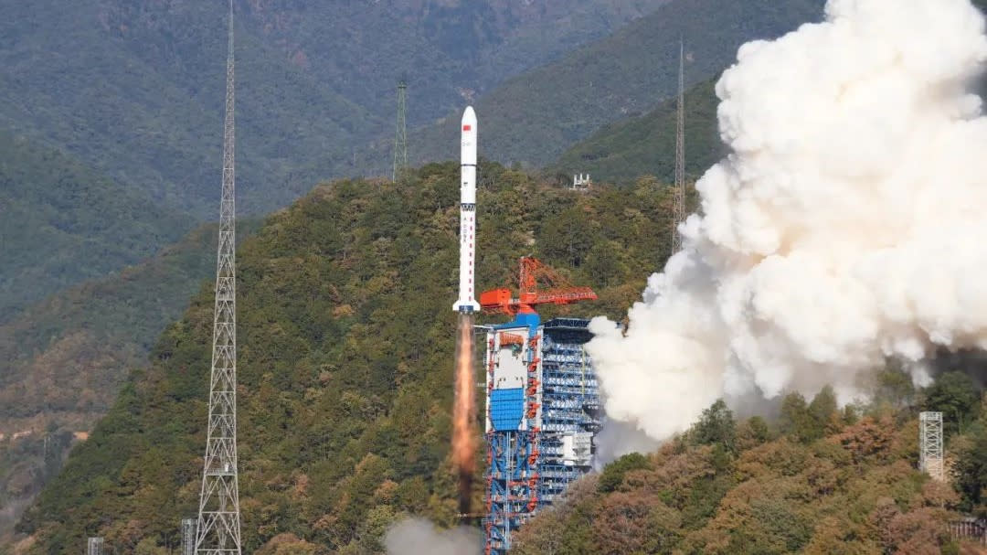  A small white rocket lifts off from forested mountain terrain. 