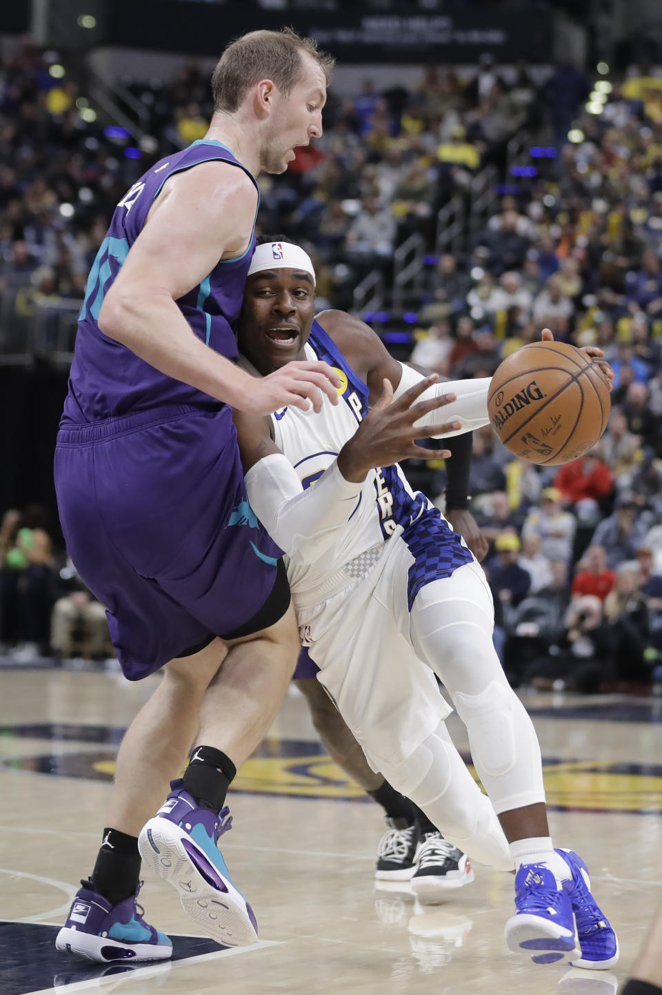 Indiana Pacers' Aaron Holiday, right, drives to the basket against Charlotte Hornets' Cody Zeller, left, during the second half of an NBA basketball game, Sunday, Dec. 15, 2019, in Indianapolis.(AP Photo/Darron Cummings)