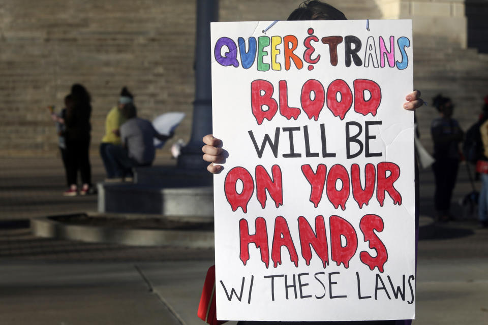 FILE - A protester outside the Kansas Statehouse holds a sign after a rally for transgender rights on the Transgender Day of Visibility, Friday, March 31, 2023, in Topeka, Kan. New laws targeting LGBTQ+ people are proliferating in GOP-led states, but often absent from policy decisions is a clear understanding of how many people will be directly affected. (AP Photo/John Hanna, File)