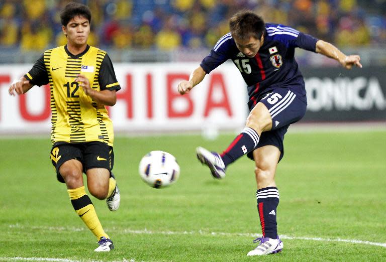 Manabu Saito of Japan (R) shoots the ball past Nazmi Faiz of Malaysia, in Bukit Jalil, some 20 km south of Kuala Lumpur, in 2012